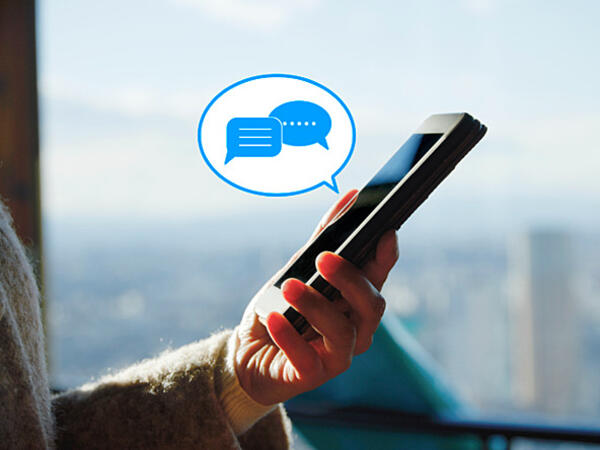 person holding phone, graphic of speech bubble with message icons